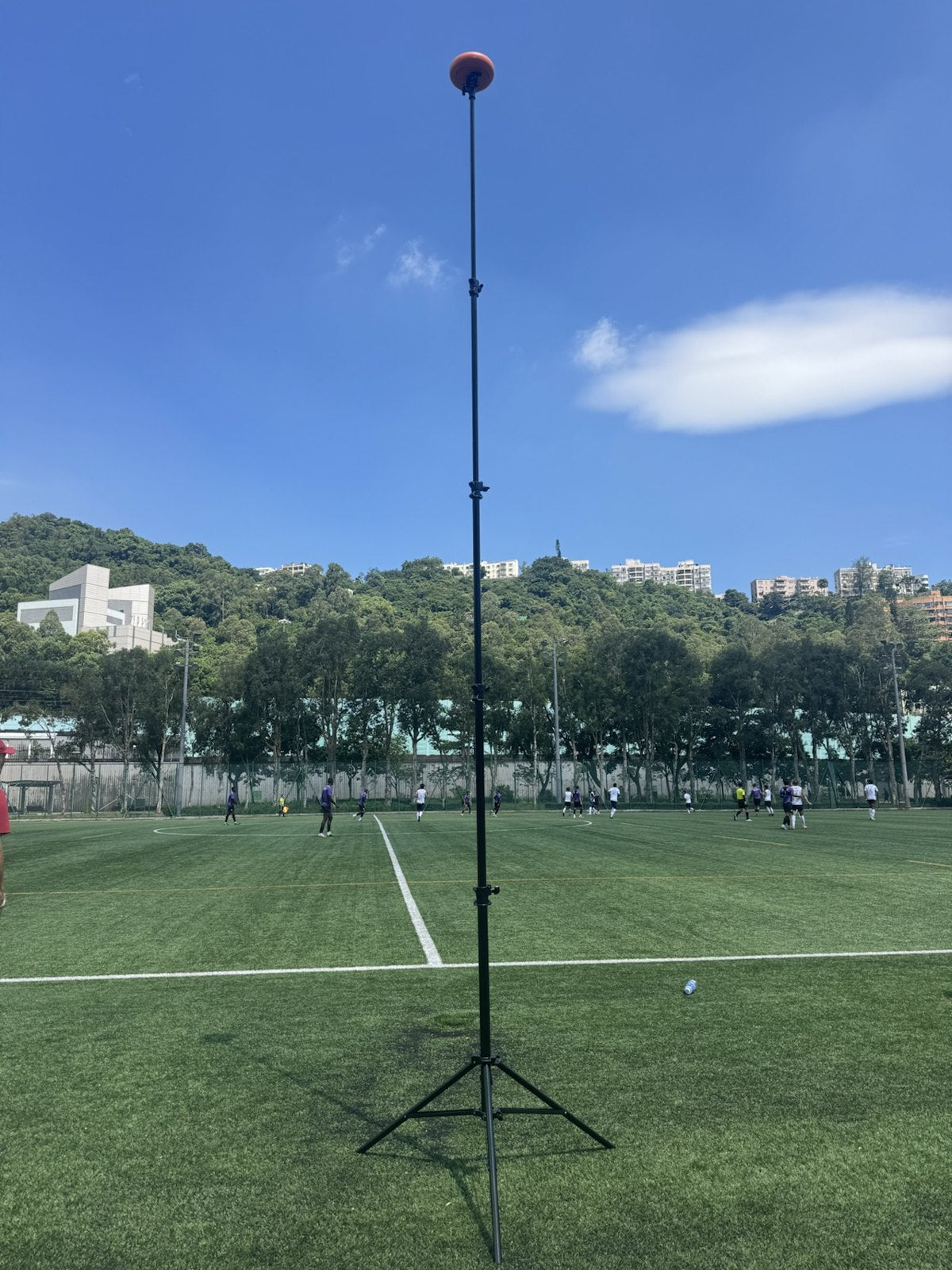 Ballr AI Sports Camera on a fully extended tripod at the side of a football pitch during a match
